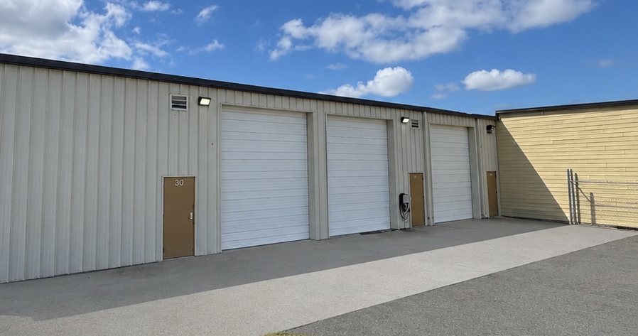 The three drive-in overhead doors and a man door along the elevation at 101 Austin Bradley Lane, opening onto the paved apron