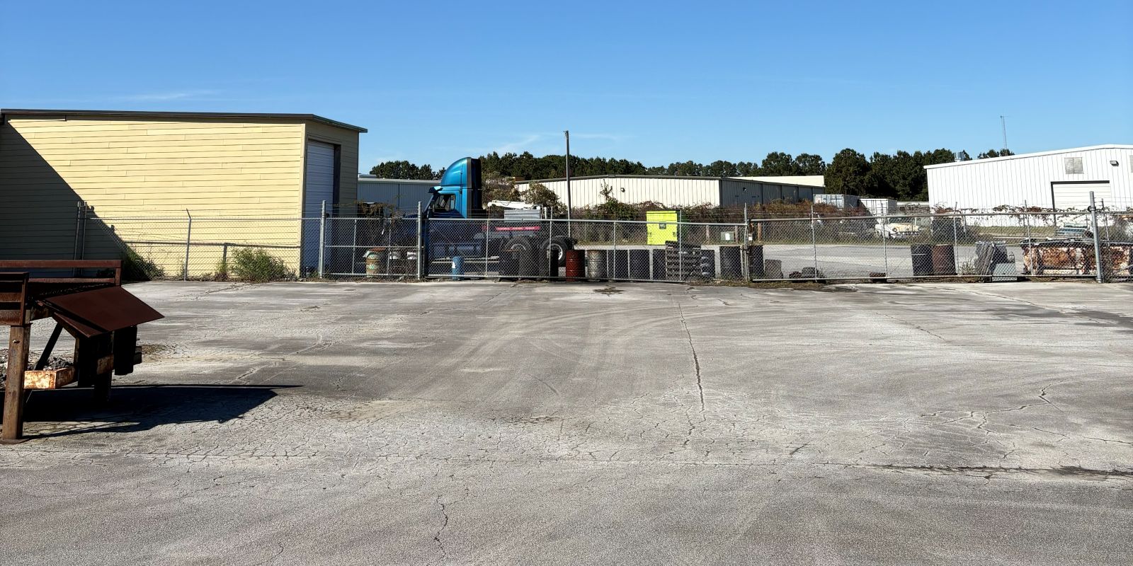 Fenced, paved outdoor storage and laydown yard at 101 Austin Bradley Lane, with a tractor unit parked behind the chain-link gate
