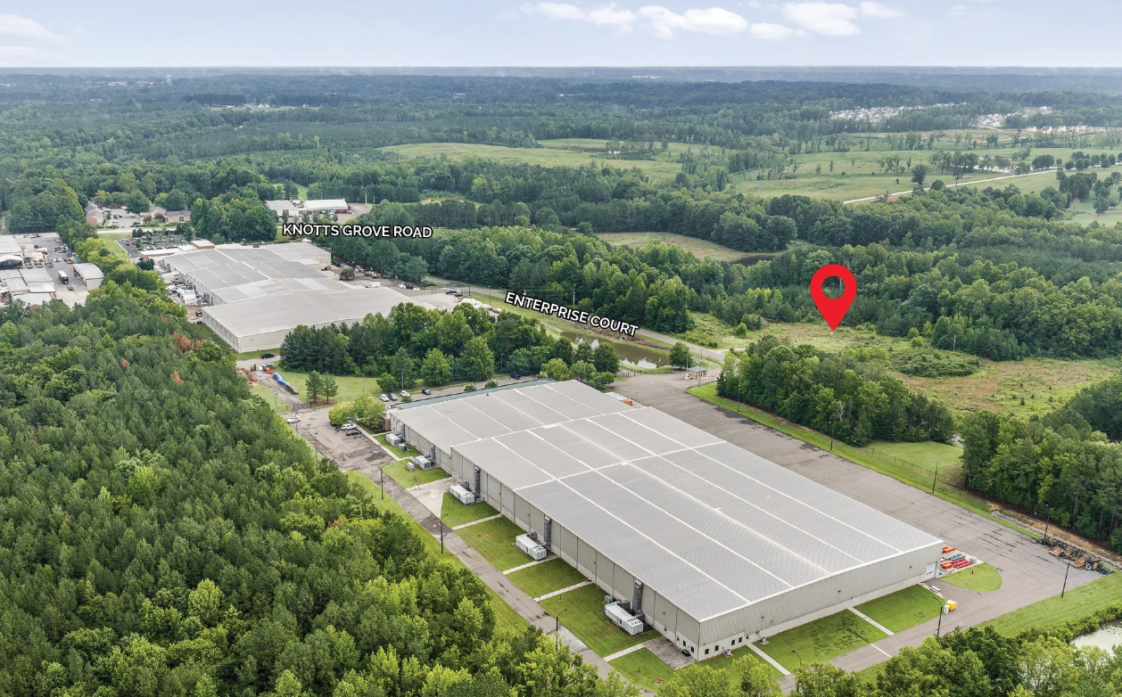 Aerial looking across a large industrial building toward the 105 Enterprise Court site, marked with a red pin along Enterprise Court, with Knotts Grove Road and the business park to the left