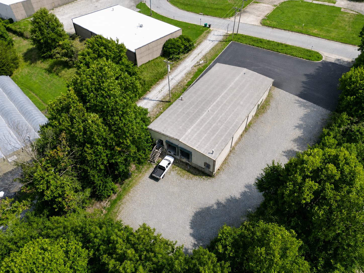 Aerial view of 1310 Starr Drive, a single-story metal flex industrial building in High Point, North Carolina, ringed by a gravel drive and dock court with wooded land beyond