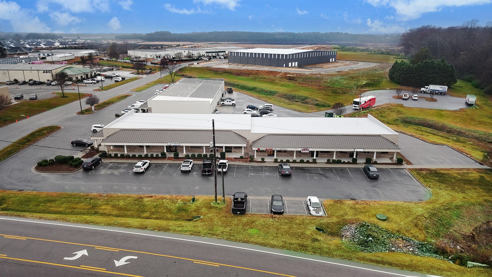 Aerial view over 1990 Allen Road looking across the park toward neighbouring industrial and warehouse buildings, a self-storage facility, and open land beyond