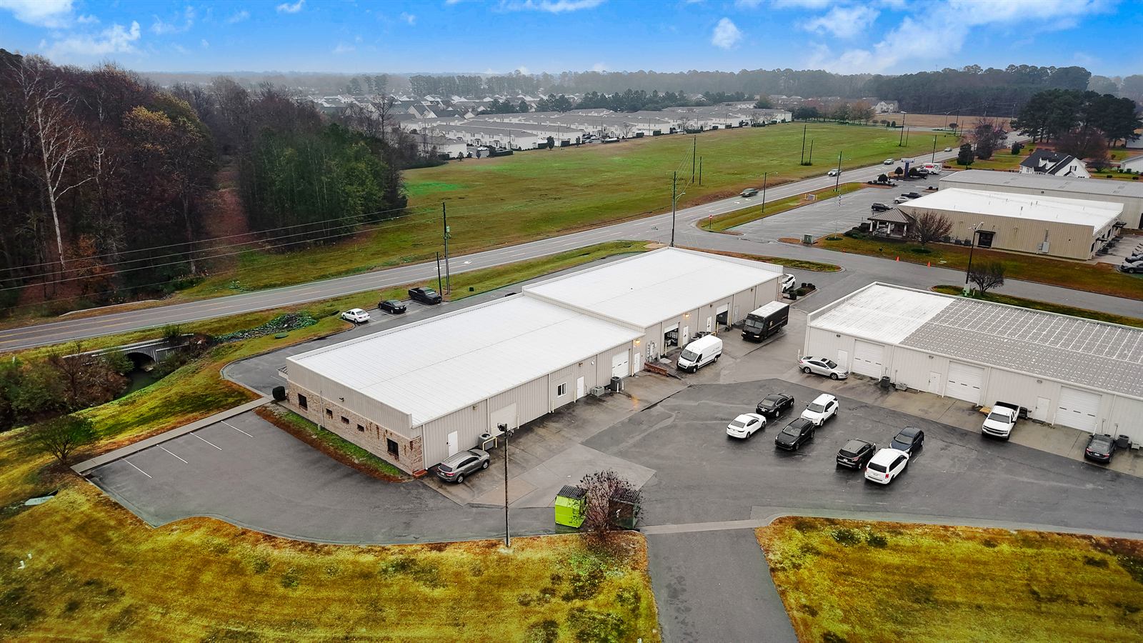 Aerial view of the rear flex building at 1990 Allen Road showing white roll-up drive-in doors along its face, service vans and a delivery truck at the bays, and parking between the two buildings