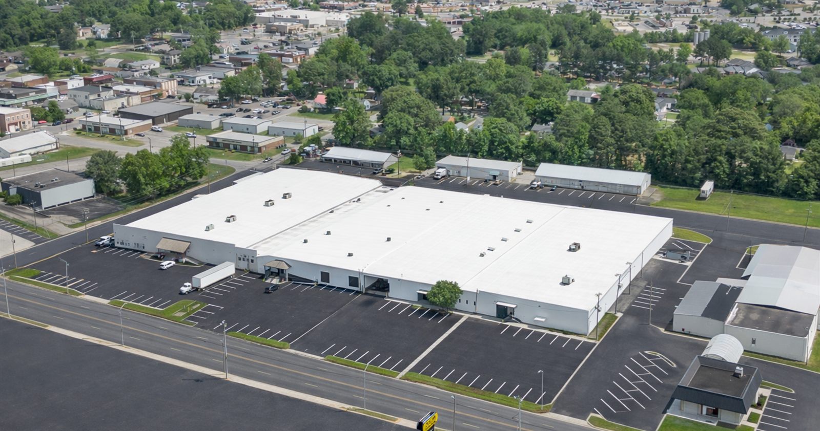 Aerial view of the Lee Avenue Industrial Complex at 2613 Lee Avenue in Sanford, North Carolina, showing the white-roofed warehouse building, striped surface parking, and the surrounding downtown