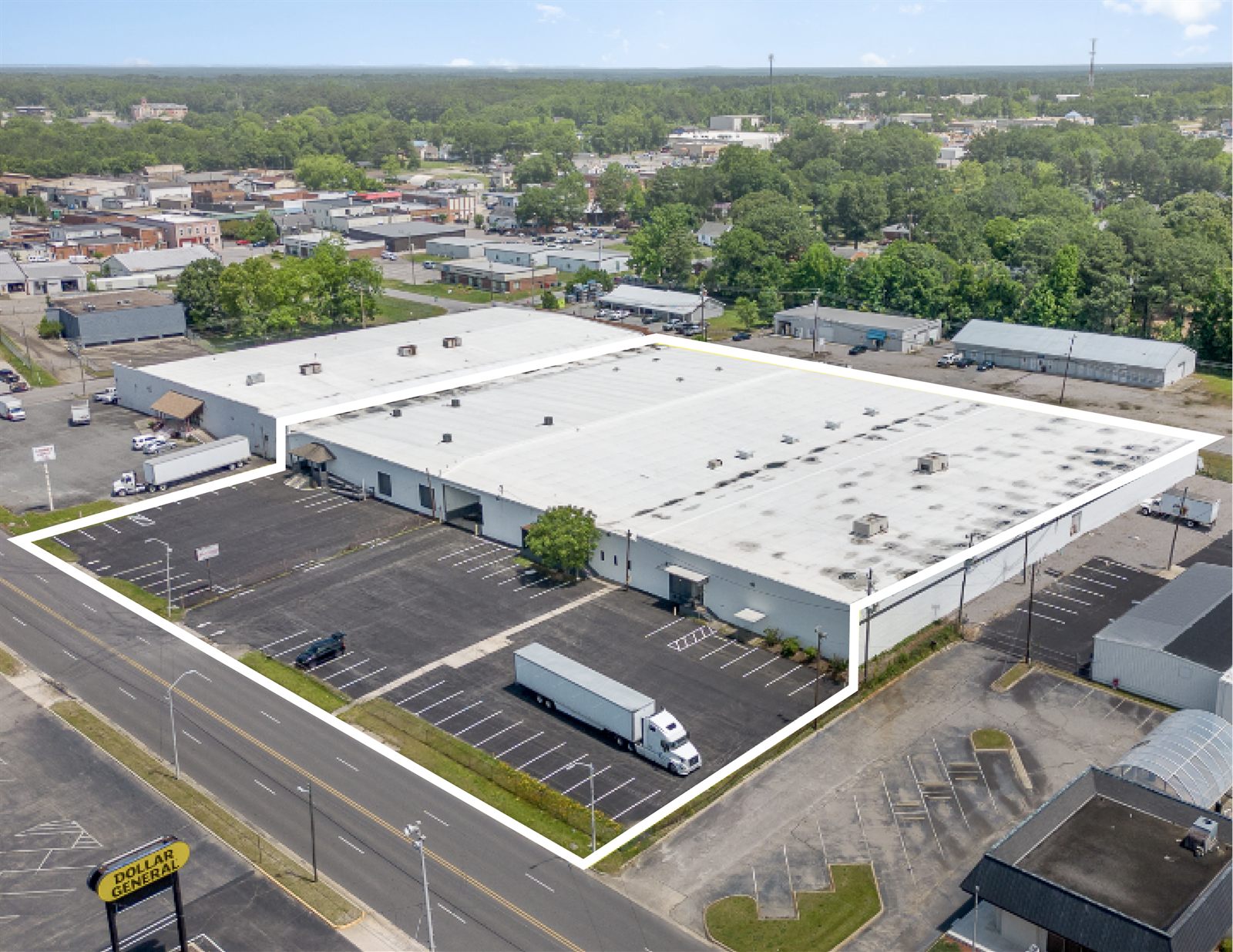 Aerial of 2613 Lee Avenue with the property boundary outlined in white, showing the building footprint, the surface parking, and the neighboring downtown Sanford blocks