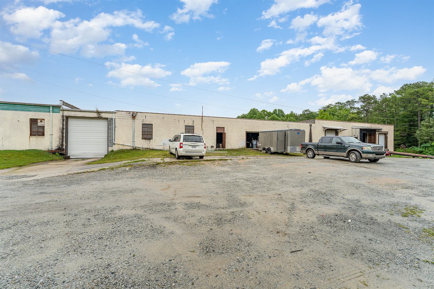 Front elevation of 314 Mandustry Street showing painted masonry walls, an oversized drive-in door, service entries, and a gravel yard with room to park trucks and trailers