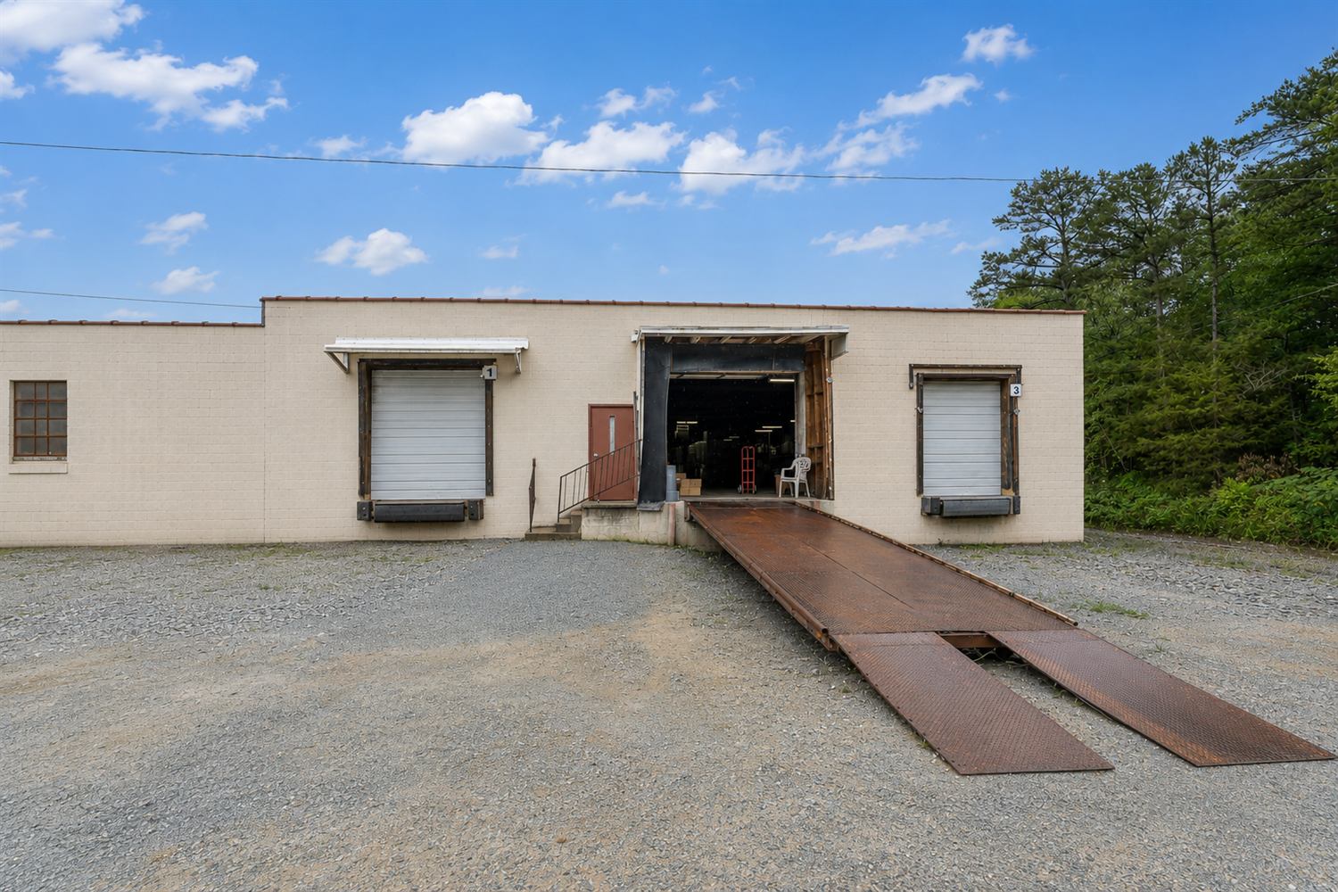 Dock-high loading at 314 Mandustry Street: two overhead dock doors flanking an open bay with a steel drive-up ramp leading into the building