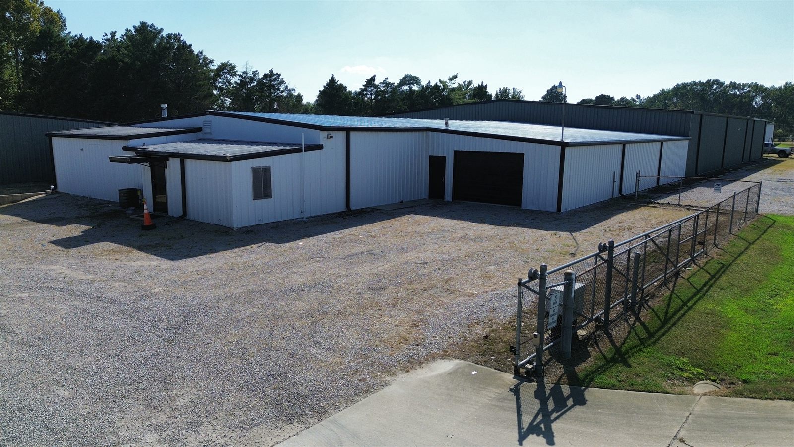 White metal warehouse at 4734 Potato House Court with a drive-in door, behind a gated gravel lot