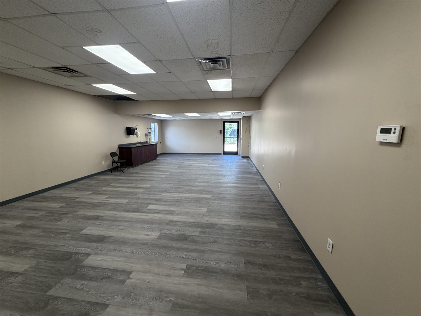 Renovated office at 4734 Potato House Court with wood-look plank flooring, fresh paint, and a drop ceiling with LED panel lights