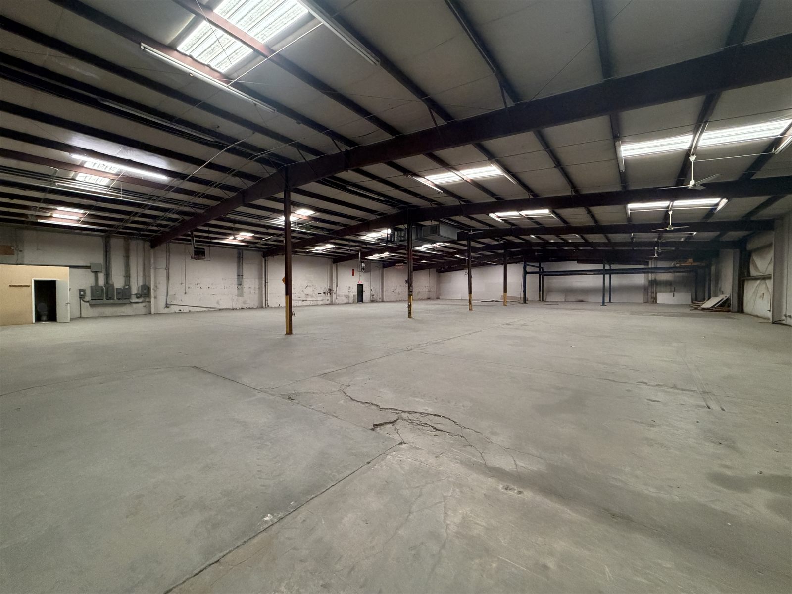 Wide, empty warehouse bay at 4734 Potato House Court under steel beams and skylight panels