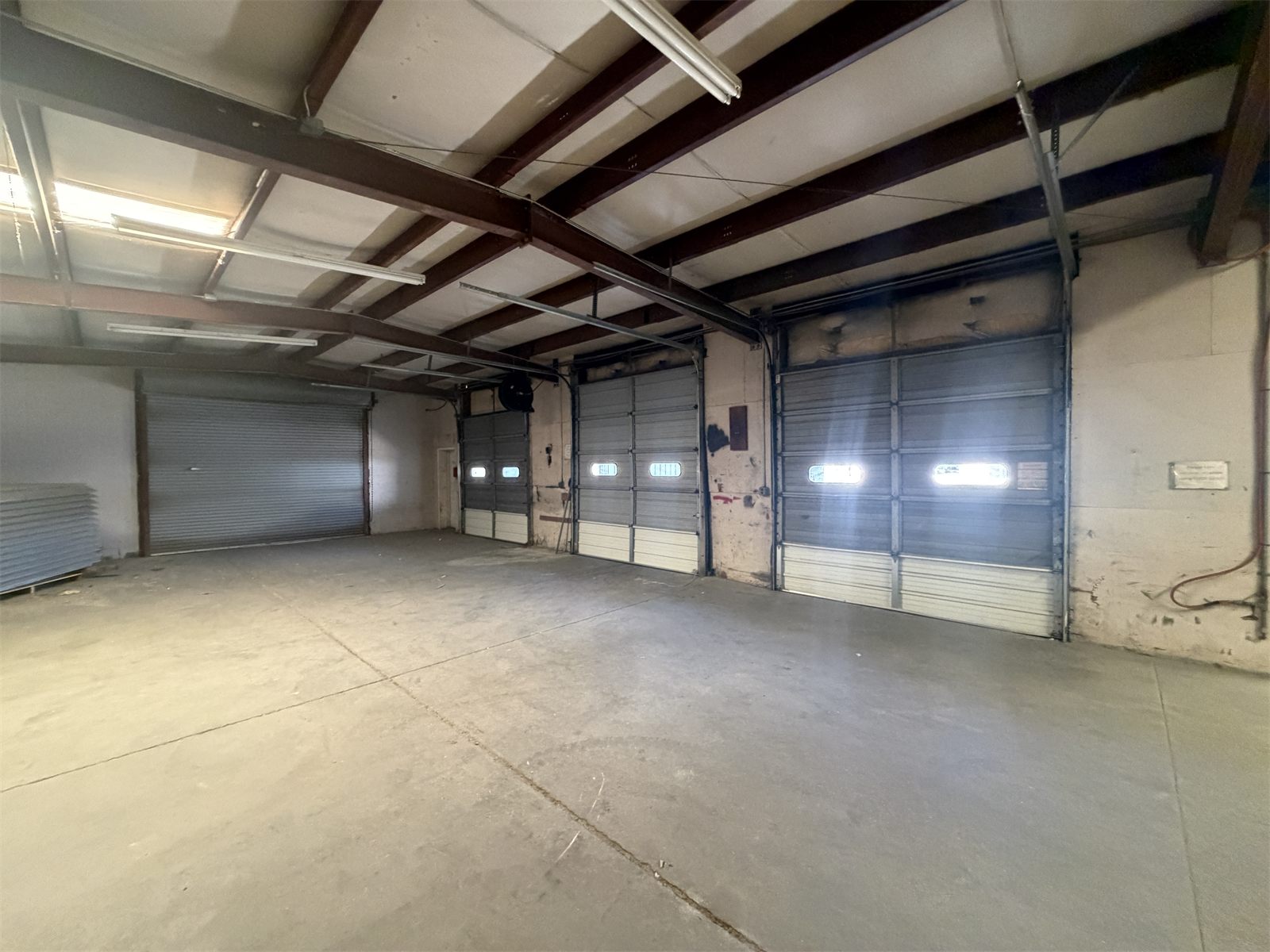 Warehouse interior at 4734 Potato House Court with a row of roll-up drive-in doors along the far wall