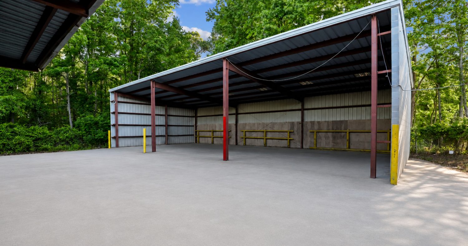 Open-sided covered shed at 6863 NC-56 with red steel columns and a concrete slab, for equipment and material staging