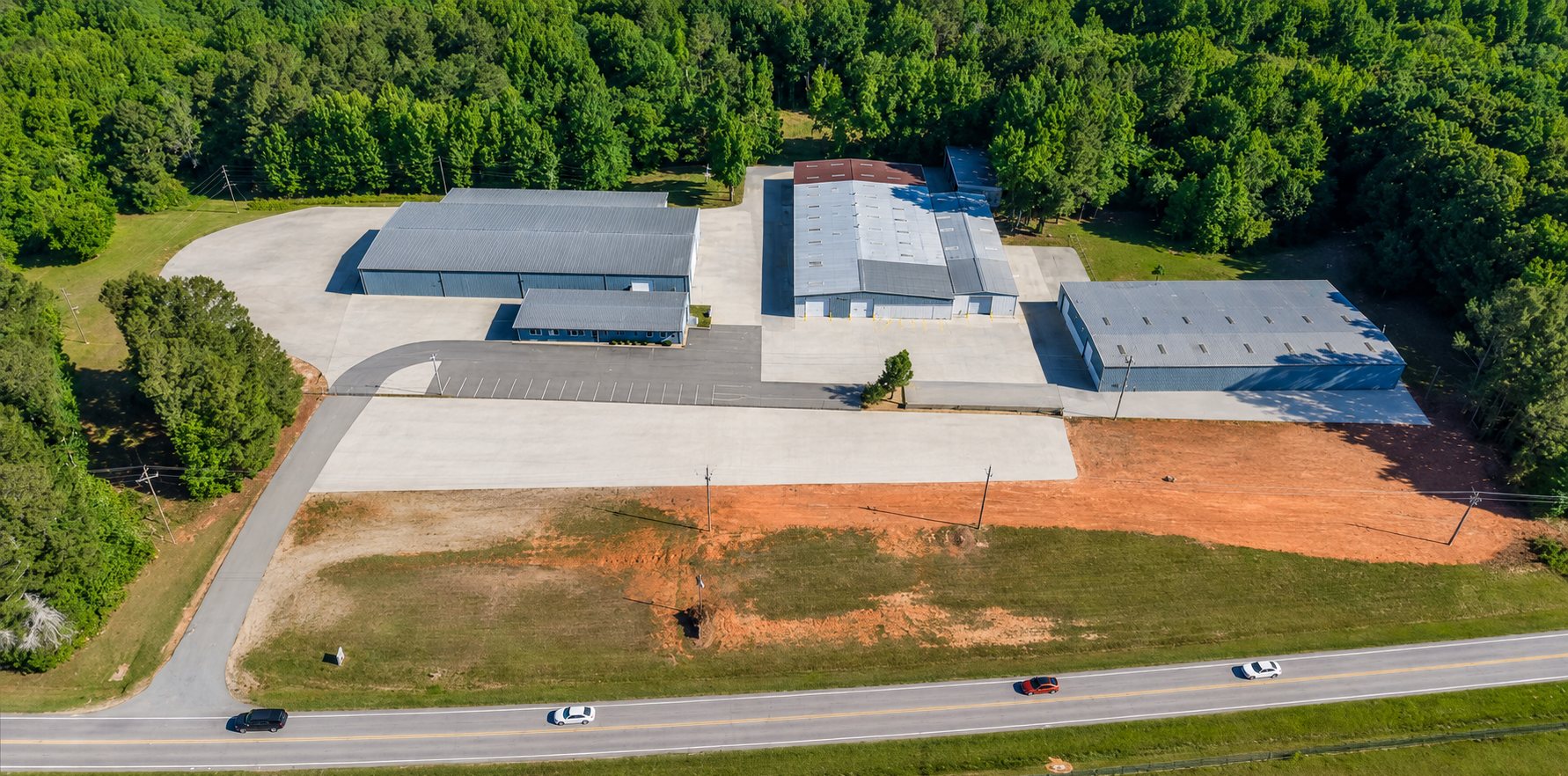 Aerial view of the 6863 NC-56 industrial campus in Franklinton, North Carolina, showing four buildings, concrete truck courts, and the open laydown yard in the foreground