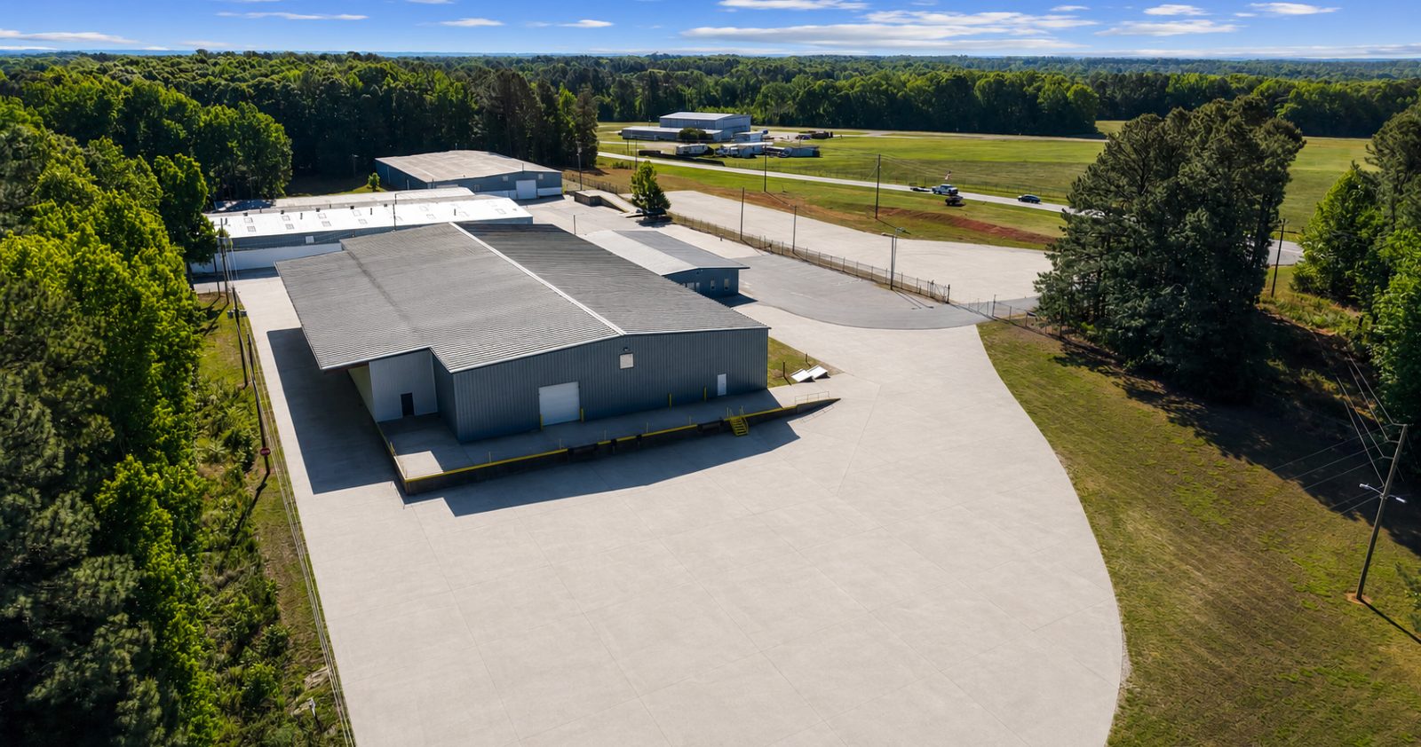 Aerial view of the broad concrete truck court at 6863 NC-56 wrapping a warehouse building, with the loading dock along the near elevation