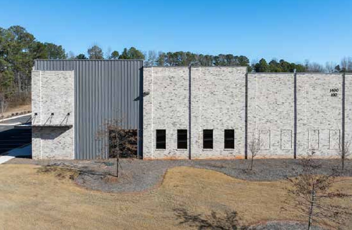 Corner of 74 South Business Park, the completed Woodlands prototype, showing the metal-clad entry tower, brick veneer bays, a projecting canopy, and suite numbering